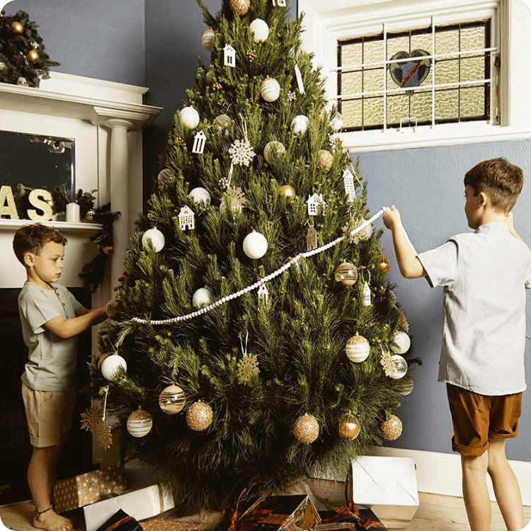 Image of two young children decorating a Christmas tree.